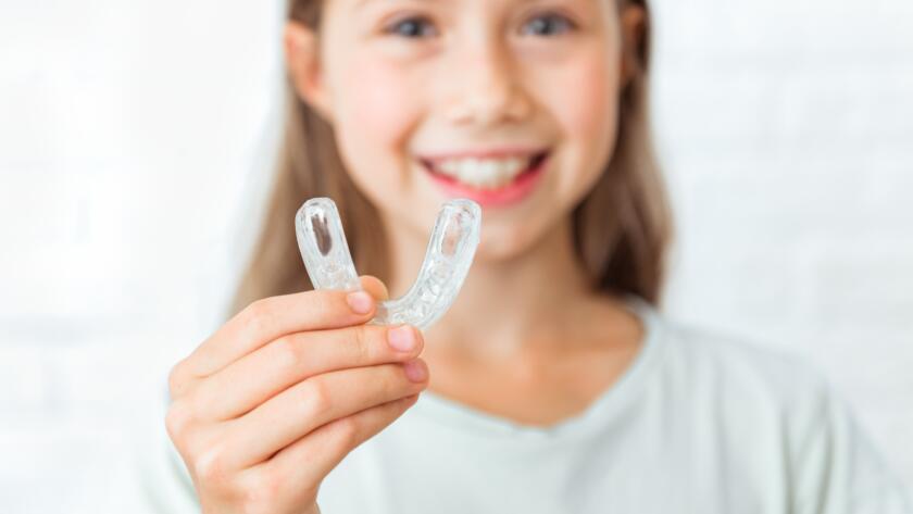 Attractive little girl shows myofunctional trainer. Help equalize the growing teeth